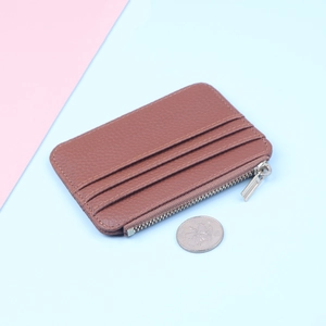 Slim brown textured card holder with zipper pocket and coin for size comparison
