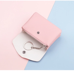 Detail view of pink lychee leather mini wallet featuring silver keychain and secure zipper