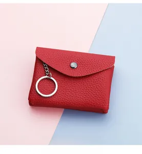Close-up of red lychee grain leather coin purse with metal buckle and silver keyring
