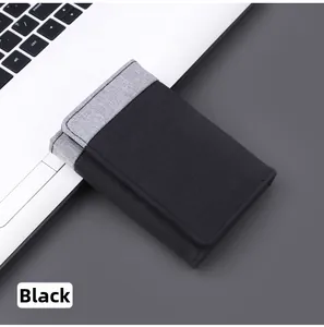 Detail of a minimalist black and grey canvas tri-fold wallet next to a laptop