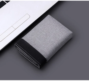 Detailed shot of grey canvas tri-fold wallet with contrast stitching on office desk