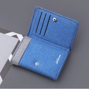Detail view of canvas tri-fold wallet showing three card slots and silver snap button