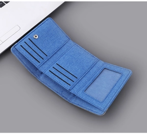 Detail view of blue canvas tri-fold wallet showing multiple card slots and clear ID window