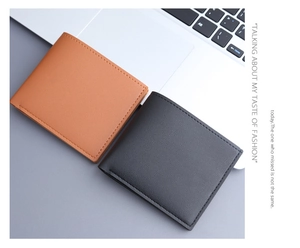 Slim bifold men's wallets in tan and dark grey on desk near white laptop
