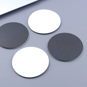 Detail shot of four circular leather car coasters in white and textured dark grey