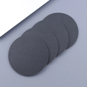Macro detail of four round grey leather car coasters with anti-slip lychee grain texture