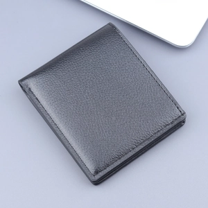 Minimalist black bifold men's wallet with lychee leather texture on a business desk