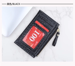 Détail d'un porte-cartes noir à texture crocodile avec fermeture éclair et fentes