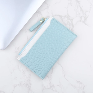 Porte-cartes zippé bleu clair à texture crocodile sur fond de marbre élégant