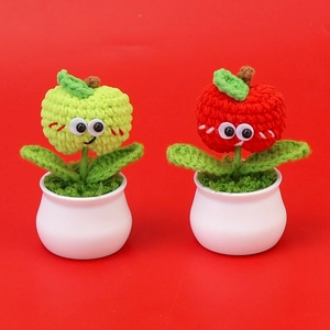Detail of two handmade crochet apple potted plants with cute faces in white ceramic pots