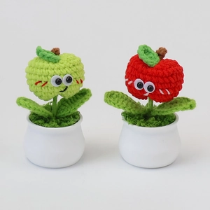 Close-up of handmade crochet apple potted plants with green leaves and ceramic pots