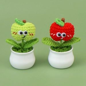 Close-up of handmade crochet apple potted plants with cute faces and white ceramic pots