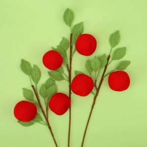 Handmade crochet red apple branches with green leaves on a soft green background