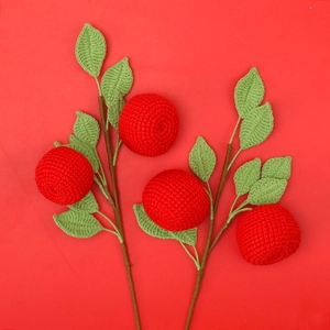 Macro detail of handmade crochet red fruit branches with green leaves on red background