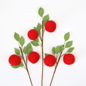 Close-up of handmade crochet apple branches with red fruits and green leaves