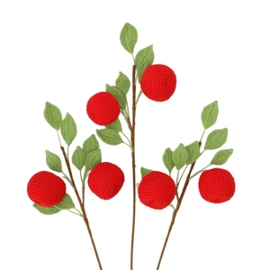 Three handmade crochet apple branches with red fruits and green leaves on white background