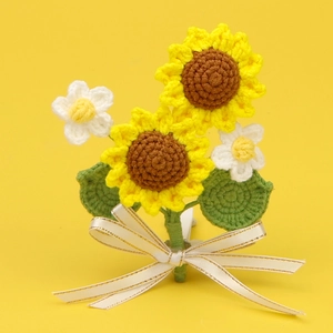 Handmade crochet sunflower and daisy bouquet with white ribbon on yellow background