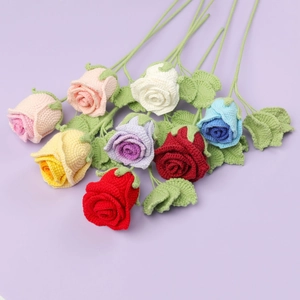 Detail of 8 hand-knitted crochet roses in various colors with green leaves on purple background
