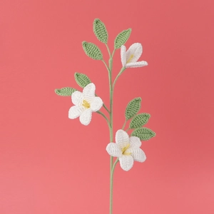 Detail von handgehäkelten Jasminblüten mit gelben Staubblättern und grünen Blättern