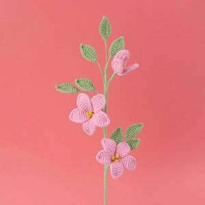 Handgefertigter gehäkelter rosa Jasminblütenstrauß mit grünen Blättern auf rosa Grund
