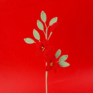 Detailaufnahme von handgehäkeltem Jasminstrauß mit roten Blüten und grünen Blättern