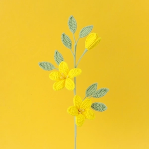 Handgehäkelter gelber Jasmin-Blumenstrauß mit zwei Blüten und grünen Blättern auf Stielen