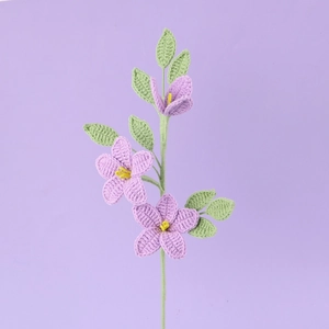 Handgehäkelter Jasminstrauß mit lila Garnblumen und grünen Blättern auf weichem Hintergrund