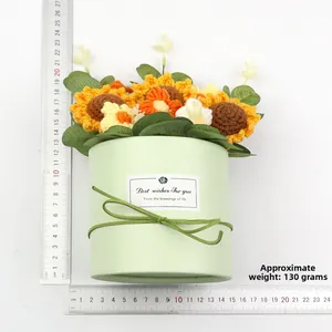Detail eines handgestrickten Sonnenblumenstraußes in grüner Box mit einem Maßstabslineal