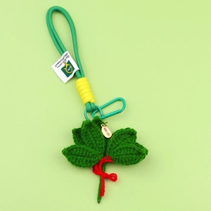Detailed macro shot of handcrafted woven green leaf charm with a red bow and gold tag