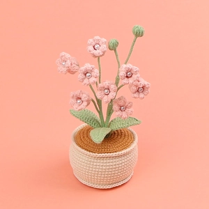 Handmade crochet pink lily of the valley potted plant with pearls on coral background