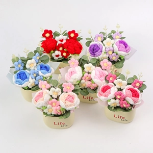 Close-up of hand-knitted potted flowers with colorful roses and green leaves on desk