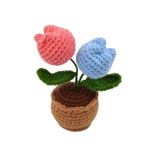 Handmade crochet tulip flower pot decor with pink and blue blossoms on white background
