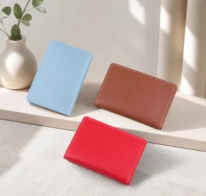 Slim leather card holder available in blue, brown, and red with white stitching detail