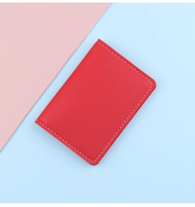 Close-up of red leather card holder with white stitching on pink and blue background