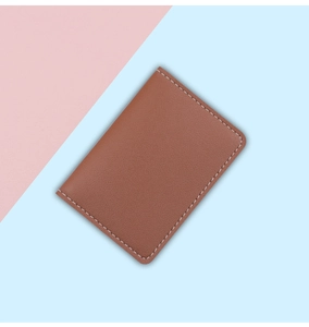 Close-up of slim brown leather card holder with contrast white stitching details