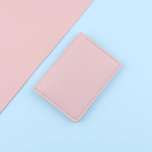 Slim pink leather card holder with white stitching on a pastel duotone background