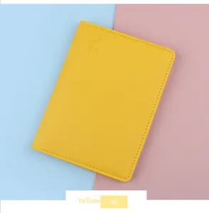 Detail view of yellow faux leather passport holder with embossed airplane icon and fine stitching
