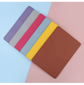 Flat lay of six colorful PU leather passport covers with minimalist embossed airplane icons