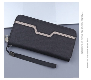 Detail of black canvas men's wallet with geometric pattern and wrist strap on laptop