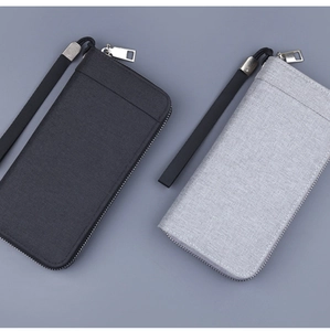 Detail view of canvas zip wallets in black and grey with woven texture and wrist strap