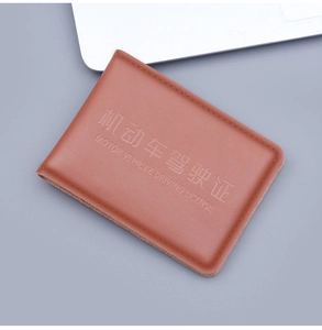 Close-up of brown leather driving license cover with embossed text and fine stitching