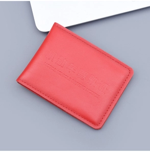 Close-up of red genuine leather driving license cover with embossed text on grey background