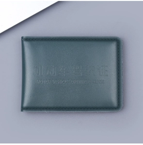 Close-up of deep teal leather driving license cover with precise stitching and embossed text