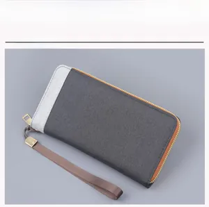Close-up of canvas wallet with gold zipper, contrast stitching and woven wrist strap