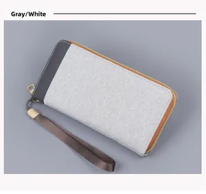 Close-up of dual-tone grey canvas clutch with orange zipper and wrist strap detail