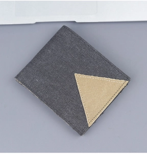 Close-up of a grey denim canvas wallet featuring precise stitching and a yellow fabric patch