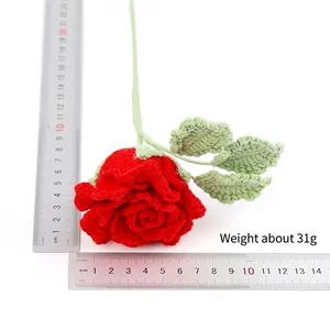 Macro detail of a handmade crocheted red rose showing yarn texture and leaf stitch