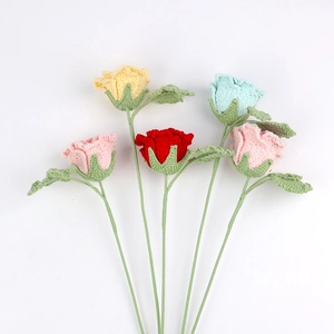 Detailed view of five handcrafted crochet roses in vibrant yarn colors with green leaves