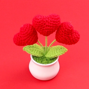 Pianta in vaso con cuori all'uncinetto fatti a mano e foglie verdi in vaso di ceramica