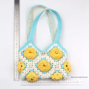 Detail view of handmade knit bag showing camellia pattern and 207g weight on white background